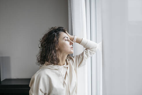 Porträt einer nachdenklichen Frau, die aus dem Fenster schaut - KMKF01191