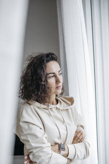 Porträt einer nachdenklichen Frau, die aus dem Fenster schaut - KMKF01192