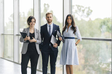 Portrait of confident business team holding portable devices - DGOF00034