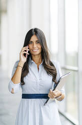 Porträt einer lächelnden Geschäftsfrau beim Telefonieren - DGOF00049