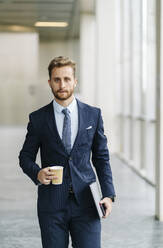 Portrait of businessman holding takeaway coffee - DGOF00051