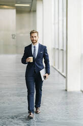 Portrait of businessman with takeaway coffee on the go - DGOF00052