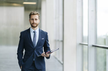 Portrait of confident businessman holding tablet - DGOF00060