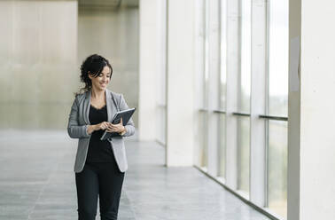 Smiling businesswoman using tablet at the window - DGOF00062