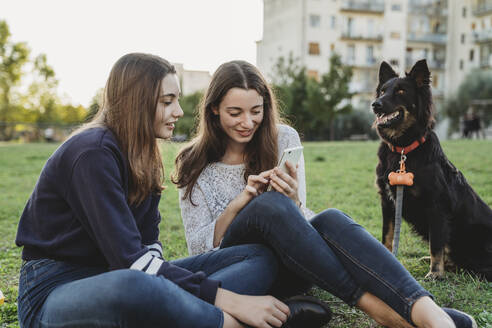 Schwestern mit Hund unterhalten sich im Park - CUF54433