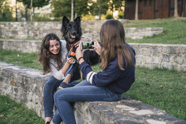 Schwestern beim Fotografieren mit Hund im Park - CUF54436