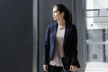 Junge Geschäftsfrau macht Pause im Korridor eines Bürogebäudes - CUF54451