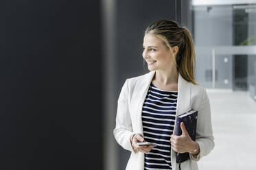 Female student with notebook at corridor of office building - CUF54470