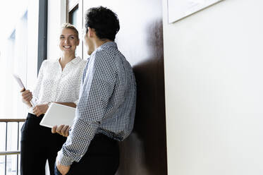 Businessman and businesswoman talking in corridor of building - CUF54492