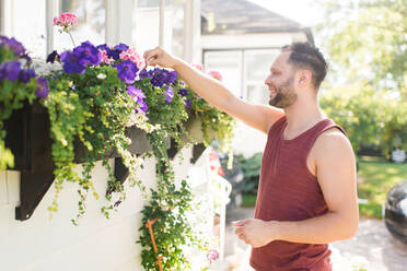 Mann kümmert sich um Blumen im Garten - CUF54517