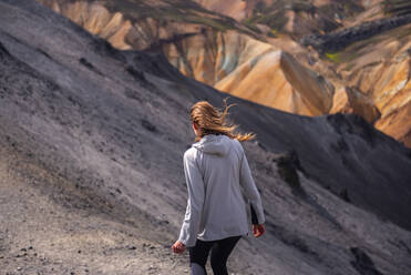 Hiker exploring mountains, Brennisteinsalda and Blᨮjkur, Landmannalaugar, Highlands, Iceland - CUF54529