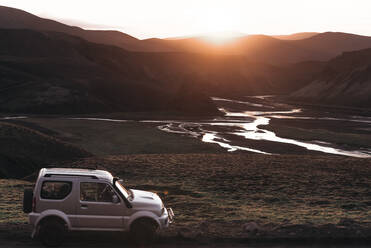 Off road vehicle in desert, sunset over mountain ranges, Landmannalaugar, Highlands, Iceland - CUF54539