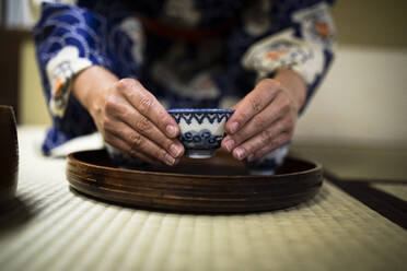 Japan, Hände einer Frau mit Teetasse während einer Teezeremonie - ABZF02895
