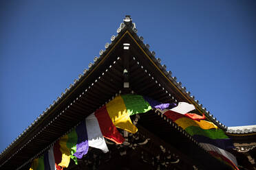 Japan, Präfektur Kyoto, Kyoto, Bunte Gebetsfahnen hängen vom Dach eines buddhistischen Tempels herab - ABZF02918