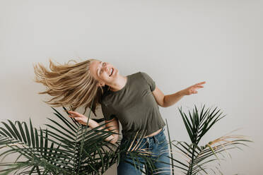 Woman swinging hair by potted palm plants - ISF23665
