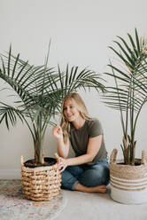 Woman admiring her house plant - ISF23667