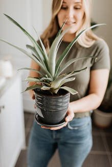 Woman carrying pot of house plant - ISF23668