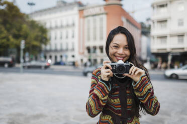 Portrait confident, carefree female tourist using camera on city street - FSIF04518
