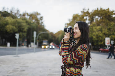Weibliche Touristin mit Kamera auf einer Stadtstraße - FSIF04519
