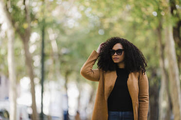 Stylish young woman in sunglasses walking in park - FSIF04533