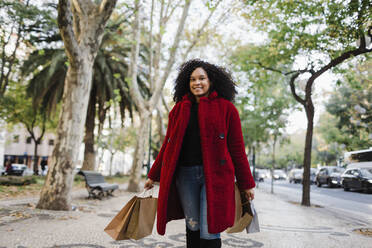 Porträt unbekümmerte junge Frau mit Einkaufstüten auf dem Bürgersteig - FSIF04542