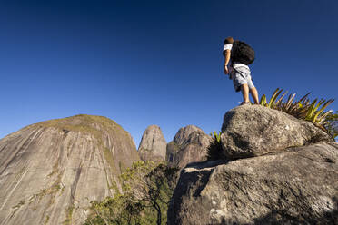 Mann posiert in der Nähe dramatischer felsiger Berggipfel im Regenwald - CAVF73021