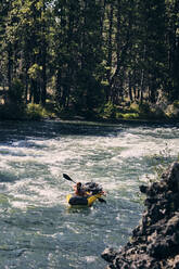 Eine Frau fährt in einem Packraft auf dem Deschutes River in Oregon durch Stromschnellen. - CAVF73048