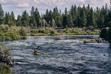 Eine Frau paddelt mit ihrem Schlauchboot den Deschutes River in Oregon hinunter. - CAVF73050