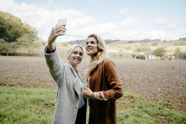 Zwei Freundinnen machen ein Selfie in einer französischen Landschaft - CAVF73079