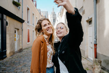 Zwei Freundinnen machen ein Selfie in einer französischen Touristenstadt - CAVF73081