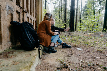 Frauen, die in einem abgelegenen Wald Videos auf ihrem Smartphone streamen - CAVF73086