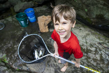 Junger Junge hält Fischernetz mit Fisch - CAVF73106