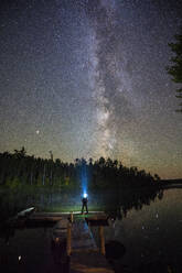 Man staring up at the Milky Way with a headlamp beam - CAVF73112