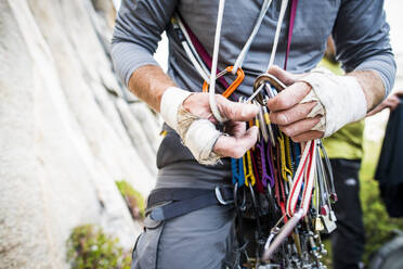 Robuste Bergsteigerhände beim Sortieren der Kletterausrüstung - CAVF73114