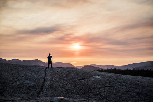 Mann mit Silhouette gegen Sonnenuntergang in den Bergen - CAVF73118