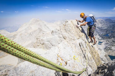 Mann beim Klettern auf einem hohen Bergrücken über dem Tal - CAVF73122