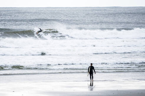 Surfer fängt eine Welle, während ein anderer Surfer aus dem Wasser geht - CAVF73126