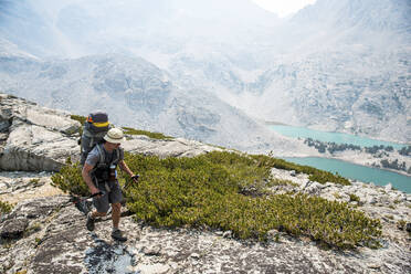 Mann wandert durch Berge mit Seen in der Ferne - CAVF73128