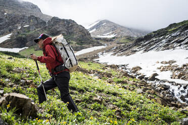 Junge entschlossene Frau beim Bergaufgehen in den Bergen - CAVF73136