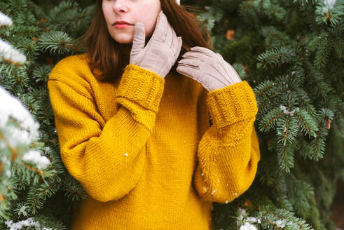 Woman looking away while standing by snow covered trees - CAVF73237