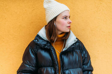 Young woman while standing against yellow wall - CAVF73239