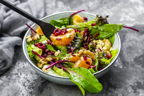 Winter salad with lettuce, tangerines, walnuts, feta and pomegranate seeds stock photo