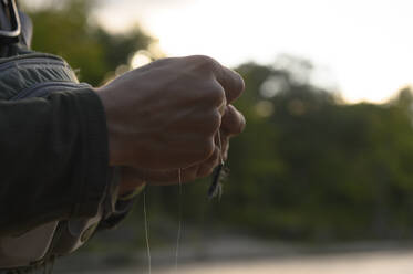 A man tying on an artificial fly called a wooly bugger - CAVF73418