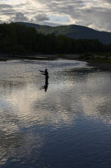 Ein Fliegenfischer wirft abends an einem Fluss. - CAVF73420