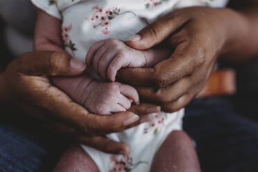 Ethnische weibliche Hände halten winzige wächserne Hände eines multiethnischen Neugeborenen - CAVF73436