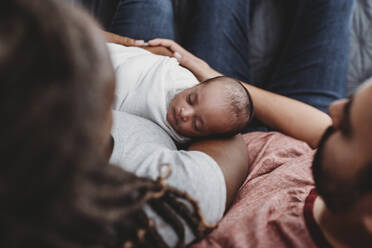 Mid-30’s multiracial couple holding their swaddled infant - CAVF73451