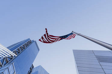 USA, New York, New York City, Direkt unter dem Blick auf den klaren Himmel über der amerikanischen Flagge und den Wolkenkratzern von Manhattan - DAMF00262