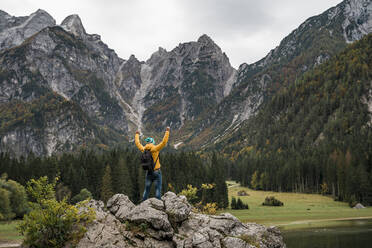 Wanderer auf einem Aussichtspunkt mit erhobenen Armen an den Laghi di Fusine, Friaul-Julisch-Venetien, Italien - MAUF03204