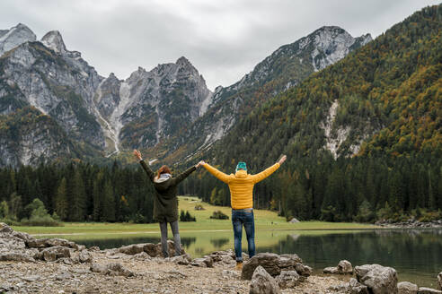 Couple with raised arms at Laghi di Fusine, Friuli Venezia Giulia, Italy - MAUF03210