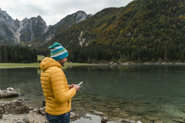 Wanderer mit Smartphone an den Laghi di Fusine, Friaul-Julisch-Venetien, Italien - MAUF03213